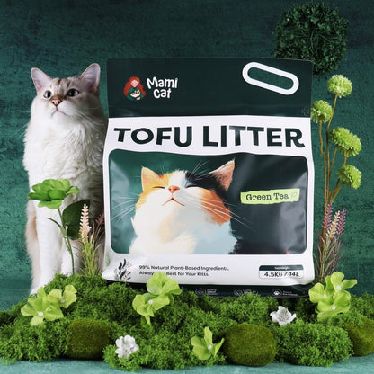 Mami Cat Tofu Litter Green Tea scent atop a bed of foliage and a cute cream cat beside.