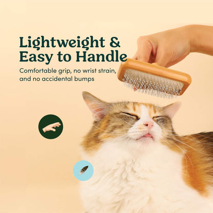 A Calico Cat being combed by Mami Cat Wooden Slicker Fur Brush. Demonstrating how easy it is to comb because of its light weight and ergonomic grip.