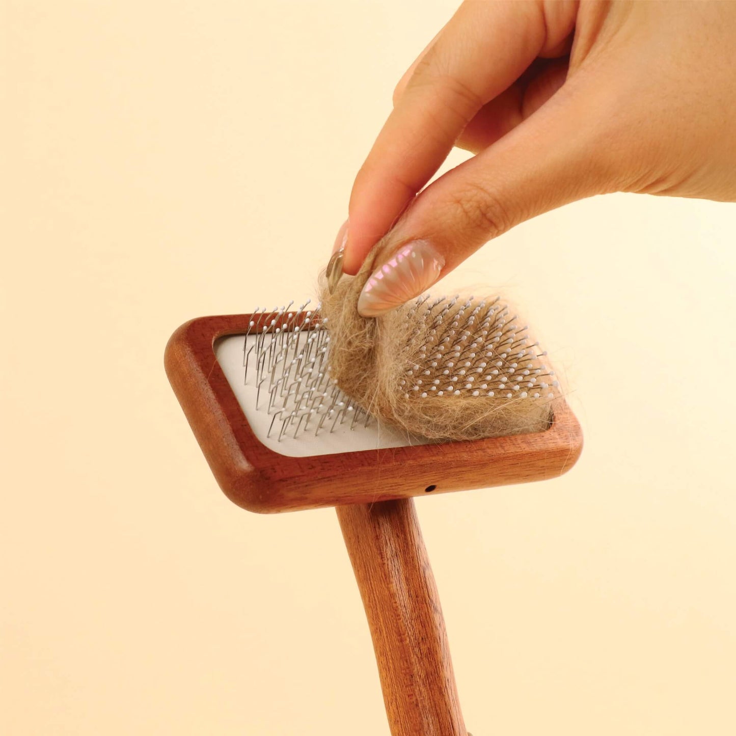 Hand Effortlessly Pinching off Accumulated Cat Fur from Mami Cat Wooden Slicker Fur Brush Comb.